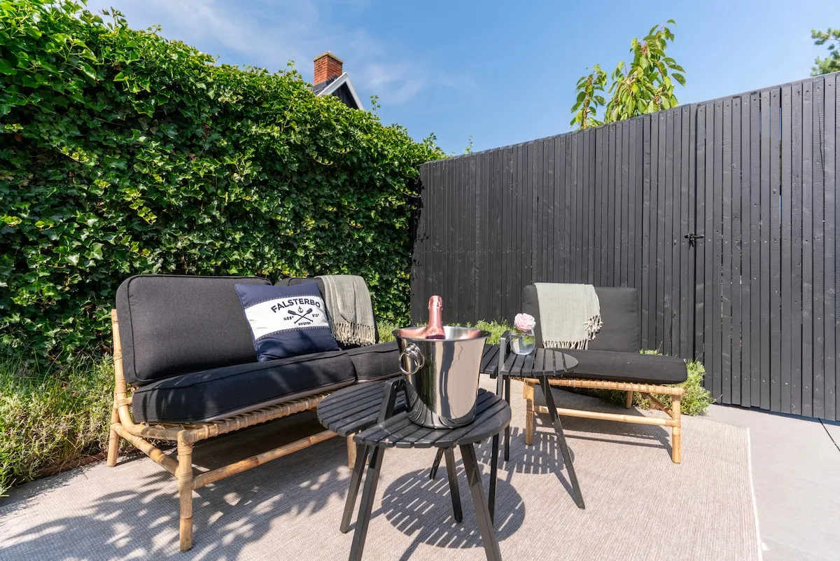 Privat uteplats med loungemöbler och gröna häckar